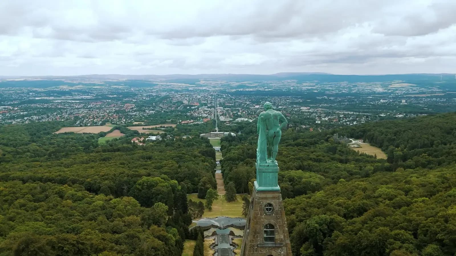 Luftaufnahme vom Herkules über den Bergpark Wilhelmshöhe: Kaskaden und Schlossachse führen hinab auf Kassel und das weite Umland.